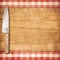 Cutting breadboard and knife over red grunge gingham tablecloth