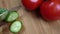 Cutting fresh green cucumber on a wooden board. Cook cut vegetables with a knife. Cuts in half.