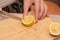 Cutting a Fresh Lemon on a Wooden Board. Hand slicing a yellow lemon on a bamboo cutting board