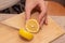 Cutting a Fresh Lemon on a Wooden Board. Hand slicing a yellow lemon on a bamboo cutting board