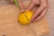 Cutting a Fresh Lemon on a Wooden Board. Hand slicing a yellow lemon on a bamboo cutting board