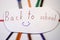A cutting inscription Back to school on white background with colourful pencils and compasses