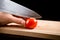 Cutting little red cherry tomato on wooden board