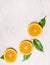 Cutting orange fruits with leaves on white wooden background