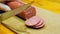 Cutting sausage on wooden chopping board. The cook cuts the sausage into pieces on a wooden cutting board. Beautiful homemade