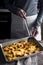 Cutting tartiflette in the baking tray on the wooden table