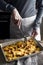 Cutting tartiflette in the baking tray on the wooden table vertical