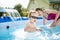 Cuty funny toddler boy and his teenage sister having fun in outdoor pool. Child learning to swim. Kid having fun with water toys.