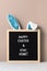 Cyan bunny ears and black felt letter board with a slogan - Happy Easter and Stay at Home on a beige background