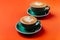 Cyan coffee cups over orange background.