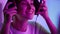 Cyber girl put headphones in pink neon lights closeup. Smiling esport gamer