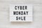 `Cyber monday sale` words on a lightbox on a white wooden background, top view. Overhead, from above, flat lay. Close-up