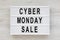 `Cyber monday sale` words on a lightbox on a white wooden surface, top view. Overhead, from above, flat lay