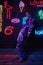 Cyberpunk shooting of model wearing contemporary sportswear against wall of neon