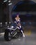 Cyberpunk woman on a futuristic motorcycle in a dark city street at night. 3D illustration