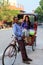 Cycle rickshaw with a tourist standing by his pedicab in Taj Ganj neighborhood of Agra, Uttar Pradesh, India