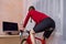 Cycling Ideas. Back View of Caucasian Sport Female Cyclist During Her Regular Excercise on Stationary Bike Trainer Indoors In