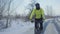 Cycling in winter. The cyclist rides on a slippery asphalt road. Man in a helmet and warm sportswear rides in a winter