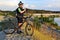 The cyclist with the bike on a sand quarry with binoculars in hand