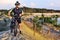 The cyclist with the bike is on a sandy hill in the sunlight