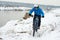 Cyclist in Blue Riding Mountain Bike on Rocky Winter Hill Covered with Snow. Extreme Sport and Enduro Biking Concept.