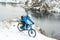 Cyclist in Blue Riding Mountain Bike on Rocky Winter Hill Covered with Snow. Extreme Sport and Enduro Biking Concept.