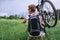 Cyclist carries bicycle in green meadow