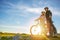 Cyclist couple with mountain bikes standing on the hill under the evening sky and enjoying bright sun at the sunset.