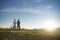 Cyclist couple with mountain bikes standing on the hill under the evening sky and enjoying bright sun at the sunset.