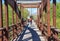 cyclist with helmet riding his mountain bike crossing a wooden brown bridge in a sunny day. Rider wears a red sweeter. Horizontal