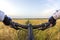 The cyclist holds the handlebars of a bicycle with his hands on the background of a wheat field. Sports and travel