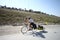 The cyclist on a long journey is in motion on the road with a trailer carrying his load at the back.