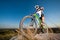 Cyclist with mountain bike on the hill under blue sky