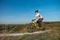 A cyclist in an orange hoodie rides a bike along a mountain path. The concept of extreme sports.