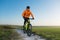 A cyclist in an orange hoodie rides a bike along a mountain path. The concept of extreme sports.