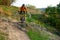 Cyclist in Orange Riding the Mountain Bike on the Autumn Rocky Trail. Extreme Sport and Enduro Biking Concept.