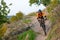 Cyclist in Orange Riding the Mountain Bike on the Autumn Rocky Trail. Extreme Sport and Enduro Biking Concept.