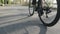 Cyclist pedaling on bicycle back follow shot. Bicycle wheel spinning. Road cycling in the city park. Slow motion