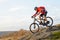 Cyclist in Red Jacket Riding the Bike Down Rocky Hill. Extreme Sport.