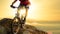 Cyclist in Red Riding the Bike Down the Rock at Sunrise. Extreme Sport and Enduro Biking Concept.