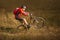 Cyclist in Red Riding the Mountain Bike on the Trail in Field. Extreme Sport Concept. Manual or Weelie on MTB.