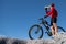 Cyclist resting and drinking isotonic drink. Backlight, sunny summer day. Extreme mountain bike sport athlete man riding outdoors