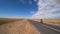 A cyclist rides on an asphalt road in the steppes of Mongolia.