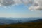 A cyclist rides on top of a mountain in summer and in the background distant mountains