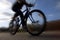 Cyclist riding on mountain bike in dramatic silhouette perspective and deliberately motion blurred