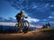 Cyclist sitting on bicycle under cloudy night sky.