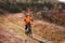 Cyclist in the sportive orange jacket riding a mountain bike along the trail in the countryside at sunset.