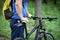 Cyclist in sportswear with bicycle against background of green s