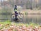 Cyclist stay at his trekking bike on small pond pier and watching swans