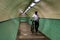 Cyclist walks his bike through tile lined underground subway pedestrian tunnel with lights